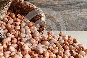 Peanuts in hemp sack on wooden background