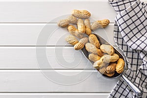 Peanuts in shell. Groundnuts in scoop on white table. Top view