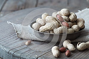 Peanuts in the shell and peeled close up in a cup. Background with peanuts. Roasted peanuts in the shell and peeled on a backgroun