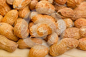 Peanuts in shelles on wooden table as a background