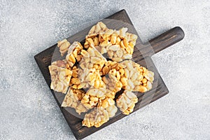 Peanuts in sugar glazed, oriental sweetness of brittle. Kozinaks are broken into pieces on a wooden Board, copy space. top view