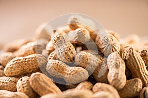 Peanuts. Unshelled nuts close up, over beige background. Roasted pile of peanuts in shell