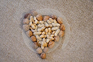 Peanuts and walnuts arranged to form a heart. Rustic background of raw yuta canvas - delicious food