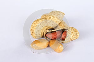 Peanuts  on white background . Two kernels are already unpacked. One of the peanuts, which was removed, revealed a red