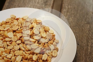 Peanuts in white plate on a wood background