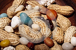 Peanuts in wooden dish with candy closeup macro