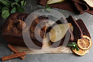 Pear bread with cinnamon, mint and dried orange slices on grey table. Homemade cake