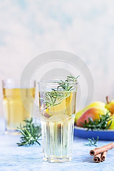 Pear cider cocktail with rosemary in tall glasses and bottle and fresh pears, blue stone background. Summer refreshment drink