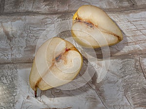Pear cut into 2 halves on a wooden background imitating brickwork