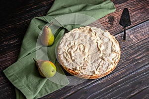 Pear meringue pie with green tablecloth on dark wood background