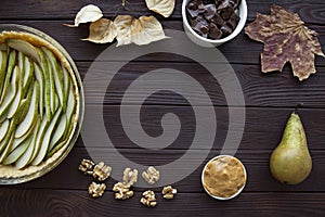 Pear pie with nuts and chocolate on brown wooden table, top view. Copy space, space for text