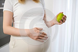 Pear in pregnant woman hands as healthy eating concept