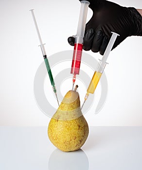A pear with a syringe filled with chemicals.