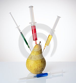 A pear with a syringe filled with chemicals.