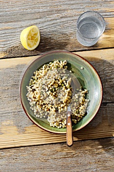 Pearl barley couscous green peas wooden table glass lemon water