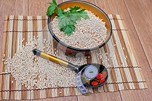 Pearl barley in a cup, nearby a spoon and a centimetric tape