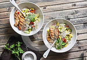 Pearl barley with seasonal garden vegetables and grilled chicken on wooden background, top view. Healthy balanced food