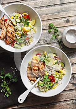 Pearl barley with seasonal garden vegetables and grilled chicken on wooden background, top view. Healthy balanced food