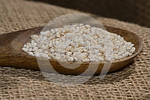 Pearl barley with wooden spoon close up surface top view background