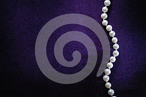 Pearl beads on purple velvet background