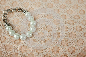 Pearl Bracelet on Vintage Peach Fabric with White Lace Pattern