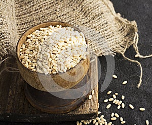 Pearl dry cereal in a vintage wooden bowl on a plain dark background for text placement and advertising. Selective focus