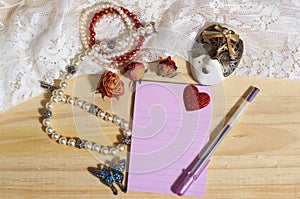 Pearl Jewelry and Butterfly Broach With Lace and Dried Roses on Wooden Background With Note Paper