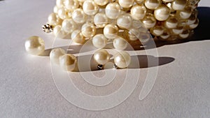 Pearl jewelry on a white background. Handmade bracelet with scattered beads. Beautiful beads of delicate champagne color. Feminine