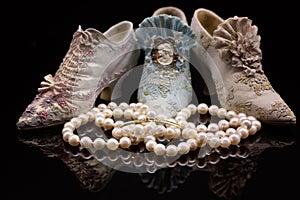 Pearl Necklace In Front Of Miniature Shoes