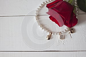 Pearl necklace with golden hearts on white wood