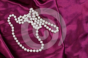 Pearl necklace on purple satin fabric background