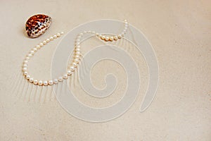 Pearl necklace on white fine sand with sea shell. Luxury resort, ocean or sea wedding concept