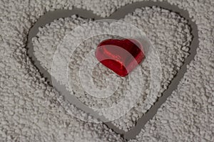 Pearl sugar is poured into a gray plate in the shape of a heart. In the middle a chocolate heart in red foil. Chocolate