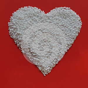 Pearl sugar is poured into a heart shape. Red rustic background. Valentine's Day, greeting card. Sprinklers and sugar photo