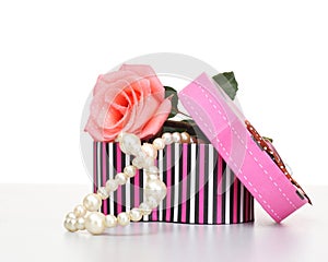 Pearls inside open gift box with pink rose