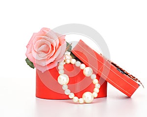 Pearls inside open gift box with pink rose