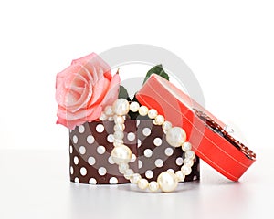 Pearls inside open gift box with pink rose