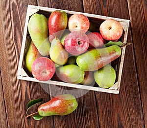 Pears and apples in wooden box on table