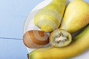 Pears, banana and kiwi fruit on wooden background with copy space. Ingredients for dietary and healthy breakfast or dinner. Top vi