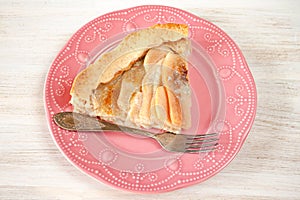 Pears and blue cheese pie quiche cake piece, slice on pink plate on rustic white table, fork.