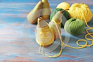 Pears with knitting yarn on wooden table