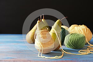 Pears with knitting yarn on wooden table