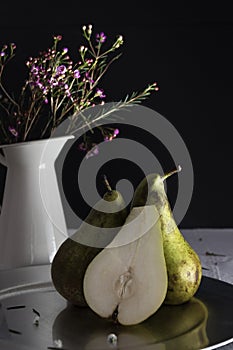 Pears and vase of flowers with black background. photo