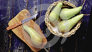 Pears in a wicker basket and another on a cutting board