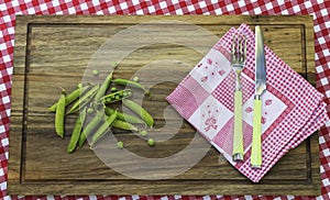 Peas and kitchen napkin on wooden board