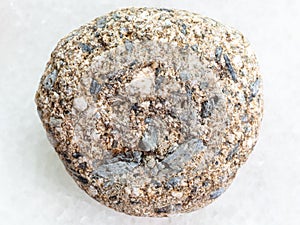pebble of Arkose sandstone on white marble photo