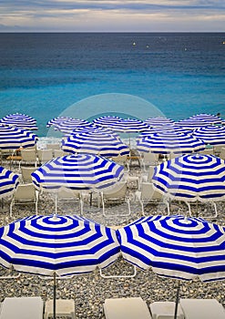 Pebble beach with beach umbrellas and chairs on Mediterranean Sea in Nice France