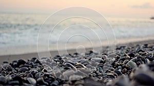 Pebble beach and blurred sea waves at pink sunset