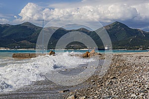 Pebble beach in the resort of Kabardinka, Krasnodar region, Black sea. Waves and surf on a pebble beach.