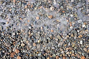 Pebble beach with sea foam and bubbles background.